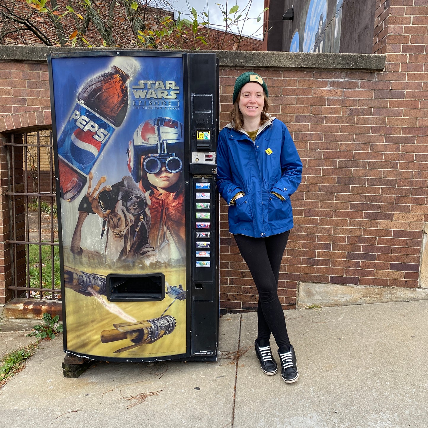 Erin, Founder of Squirrel Hill & Craft leaning up against the Phantom Menace Vending Machine